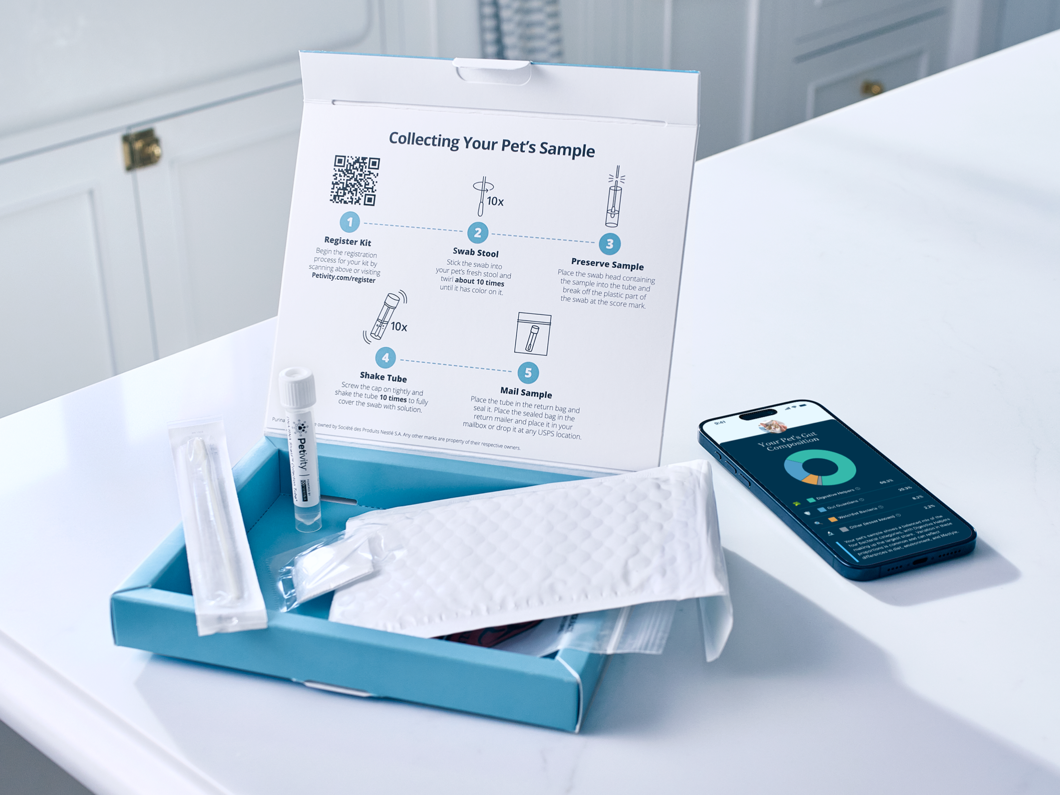 Open pet microbiome analysis kit on a bathroom counter, showing swabs, sample tube, mailing envelope, and beneficial bacteria results.