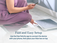 Person using a smartphone to set up the Petivity Smart Litter Box Monitor system on the floor for easy pet health tracking